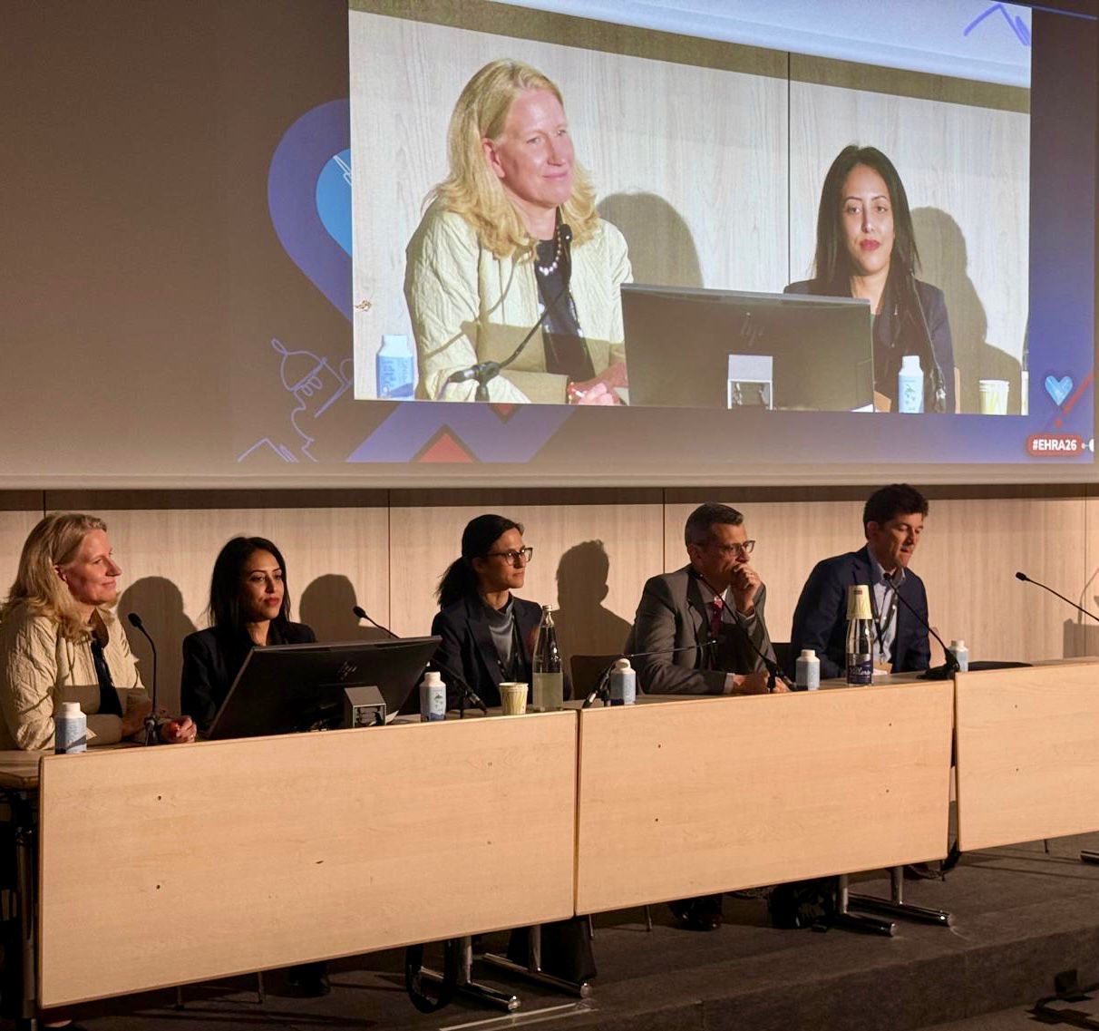 Le Dr Sana Amraoui à la tribune d’une session du congrès EHRA 2026, aux côtés de quatre autres intervenants, sous l’écran qui retransmet la séance