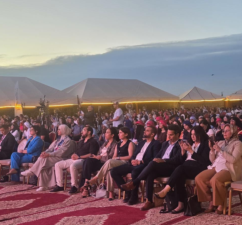 Le public du Rally IA Future Lab assis sur des tapis devant les tentes du campement de Merzouga, au crépuscule